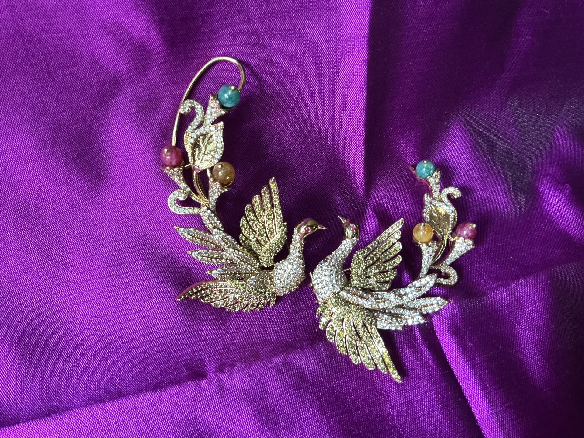 A pair of peacock ear cuffs set with stones