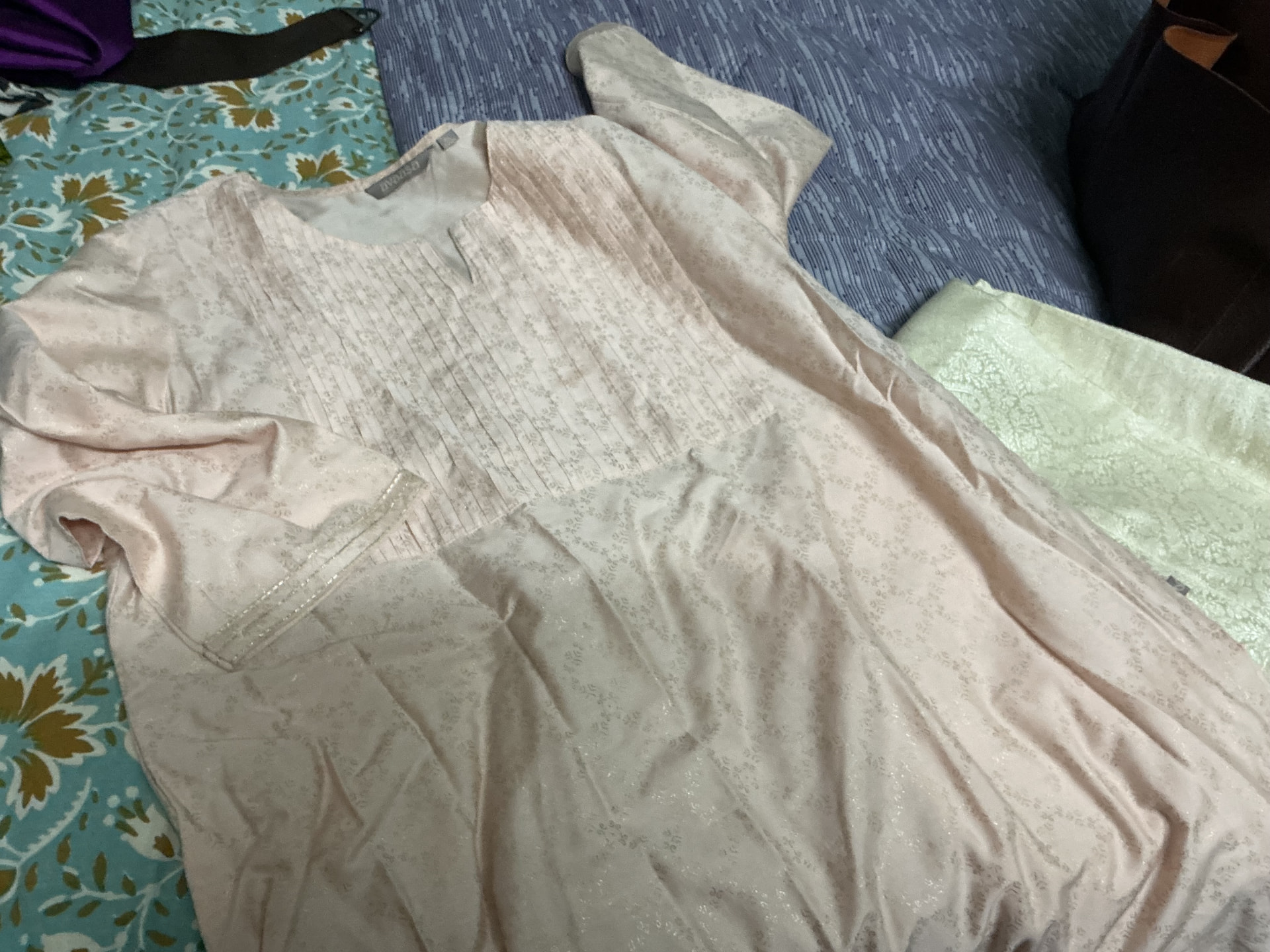 A blush pink kurta set with a sheer dupatta, laid out at home